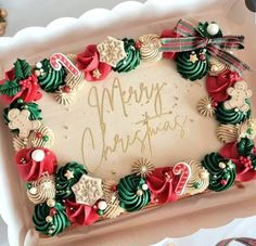 a decorated christmas cake sitting on top of a white tray with writing merry christmas written in frosting