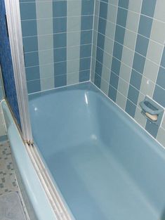 a blue bath tub sitting next to a tiled wall