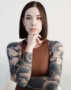 a woman with tattoos on her arms posing for the camera