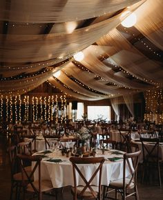 a banquet hall with tables and chairs covered in lights