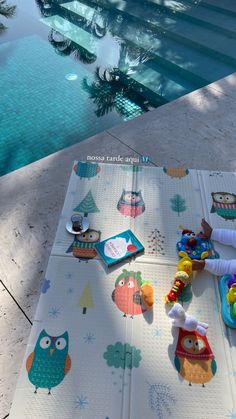 an outdoor play mat with owls on it next to a swimming pool