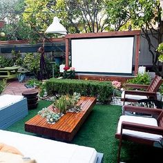 an outdoor movie is set up in the backyard with chairs, tables and couches