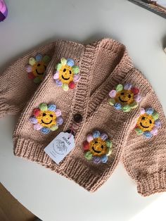 a knitted sweater with flowers on it sitting on a table next to a pair of scissors