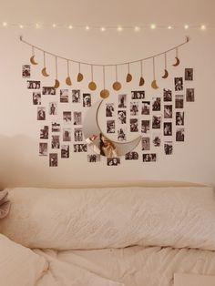 there is a bed with white sheets and pictures hanging on the wall above it,