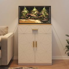 a fish tank sitting on top of a white cabinet next to a couch and chair