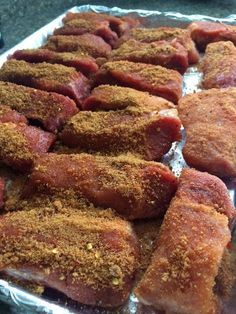 several pieces of meat sitting on top of tin foil covered in seasoning and spices