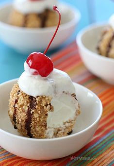 three bowls filled with ice cream, cookies and cherries on a colorful table cloth