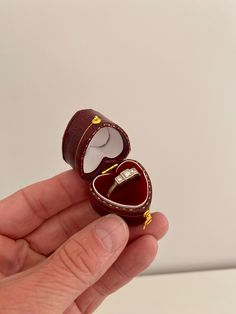 a hand holding an open ring box in it's palm