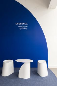 three white pedestals in front of a blue wall with the words experience on it