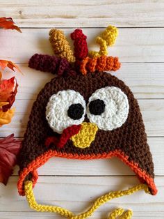 a crocheted hat with a turkey face on the front, and a yellow string attached to it