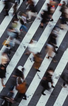 many people are walking across the crosswalk