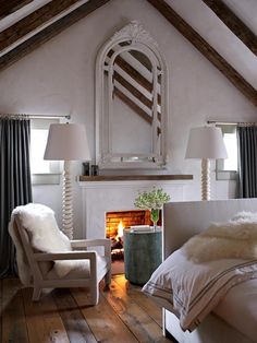 a bedroom with a fireplace, chair and mirror in the corner on the wall next to the bed