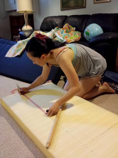 a woman is laying on the floor with a wooden board in front of her and measuring it