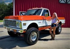 a woman standing next to an orange and white truck