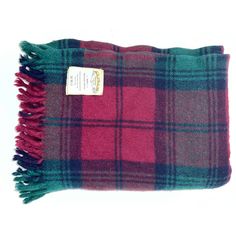 a red and green plaid blanket with fringes on the bottom, sitting against a white background