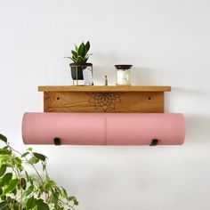 a pink yoga mat sitting on top of a wooden shelf next to a potted plant