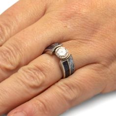 a woman's hand with a diamond ring on top of her left hand,