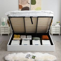 an open white bed with drawers and pillows on the floor in a room next to a painting