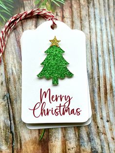 a christmas tree ornament hanging on a wooden table with red and green twine