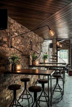 the interior of a restaurant with brick walls and wooden tables, stools and lights