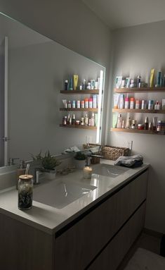 a bathroom sink with lots of bottles on the wall above it and a large mirror