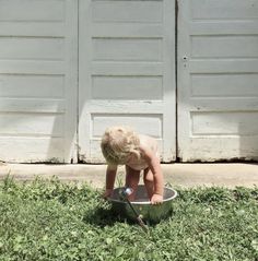 a small child in a metal tub on the grass