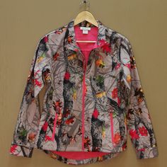 a jacket hanging on a hanger next to a wall with a pink shirt underneath it