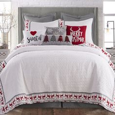 a bed covered in white and red christmas pillows next to a window with snowflakes on it