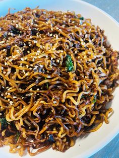 a white plate topped with noodles and broccoli on top of a blue table