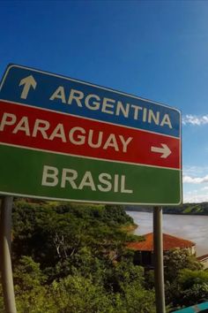 there is a street sign pointing to the right in front of a body of water