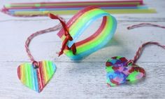 two heart shaped candy lollipops on a white wooden table next to other candies