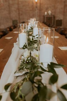 the table is set with candles and greenery for an elegant wedding reception or special event