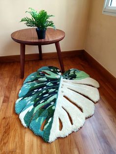 a green and white rug on the floor next to a table with a potted plant