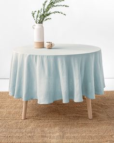 a white vase sitting on top of a wooden table next to a blue table cloth