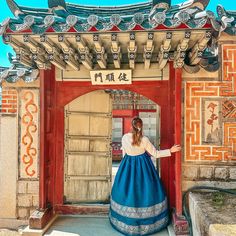 a woman in a blue and white dress is standing at the entrance to a building