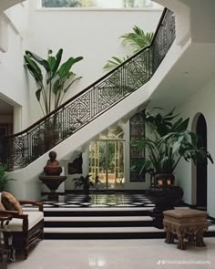 a staircase leading up to a living room with potted plants on either side and a statue in the middle