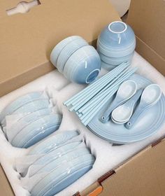 a blue dinnerware set in a box with spoons and plates on the table