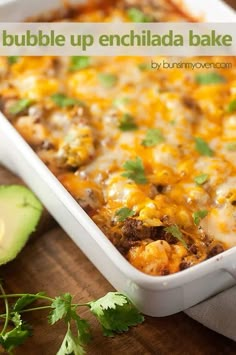 an enchilada bake in a white casserole dish with avocado on the side