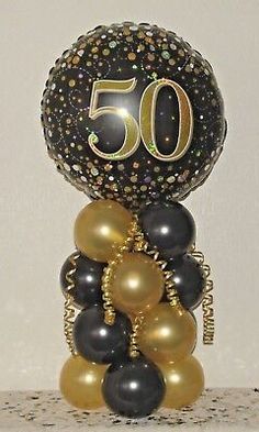 a black and gold 50th birthday decoration with balloons on top of the balloon column,