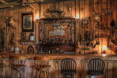 an old fashioned bar with stools and wooden paneled walls, decorated with deer heads