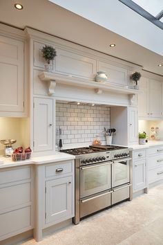 a kitchen with white cabinets and stainless steel stove top oven in the center, surrounded by potted plants