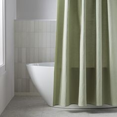 a bathroom with a tub, shower curtain and tile flooring in white and green