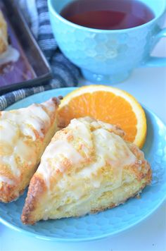 two slices of orange scones on a blue plate next to a cup of tea