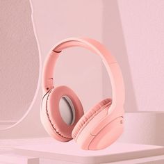 a pair of pink headphones sitting on top of a white table next to a mirror