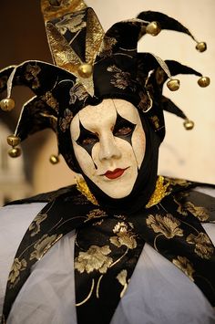 a person wearing a black and white mask with gold decorations on it's head