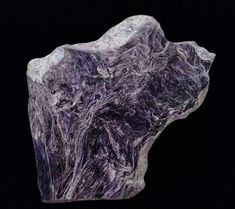 a large purple rock sitting on top of a black surface