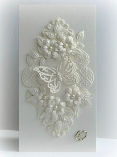 a white greeting card with lace and pearls on the front, featuring an intricate design