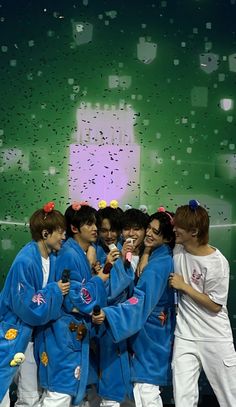 group of young men standing next to each other in front of a green screen with confetti on it