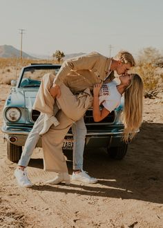 a man and woman kissing in front of a car