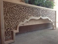 an intricately carved wooden bench with potted plants in the background